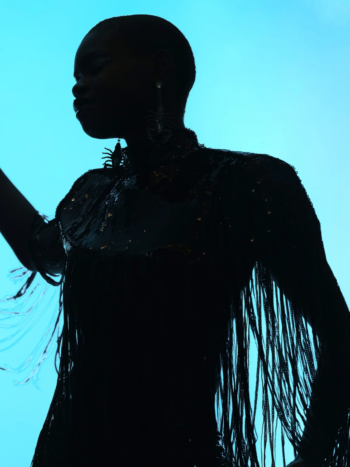 Silhouette d’une femme portant une tenue à franges sur fond bleu.