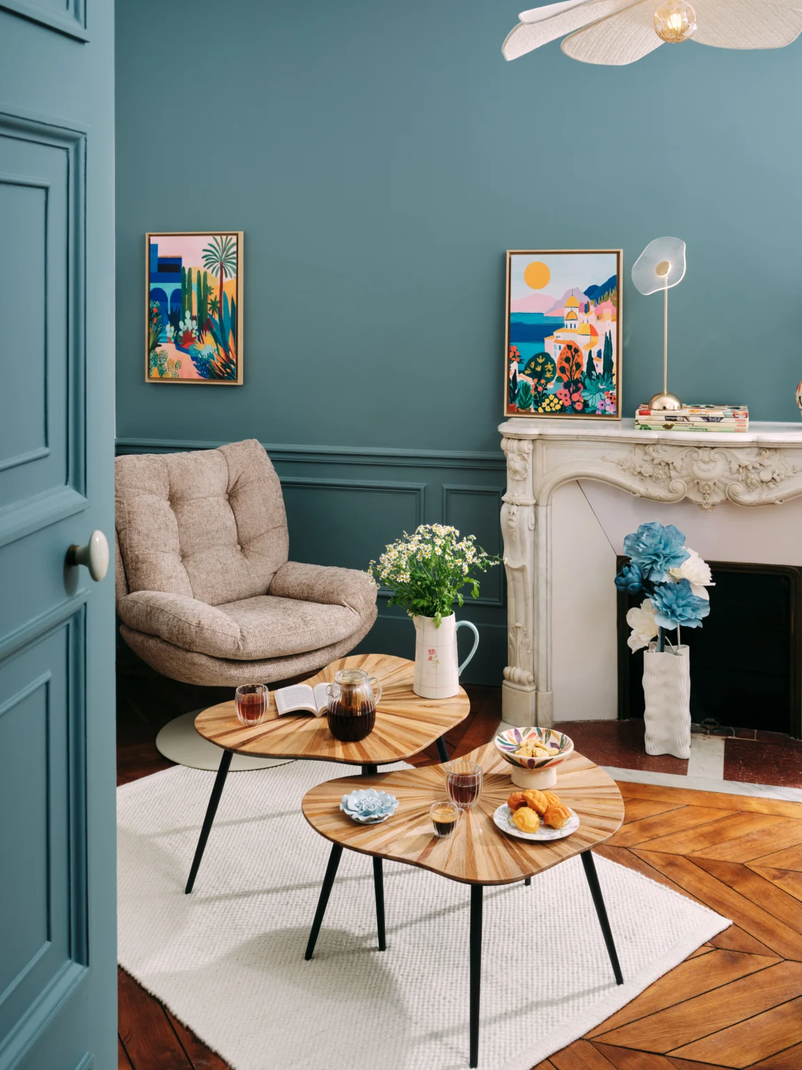 Salon aux murs bleus avec fauteuil et tables basses.
