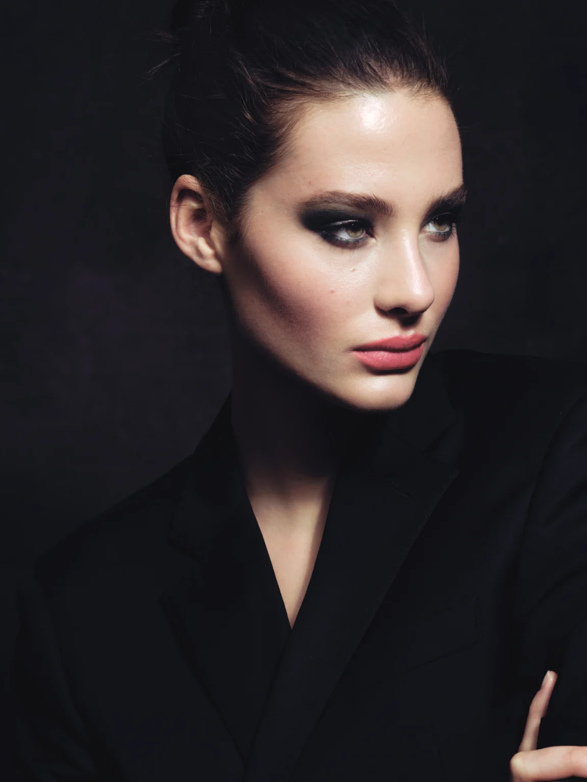 Portrait beauté d’une femme au maquillage des yeux sombre sur fond noir.