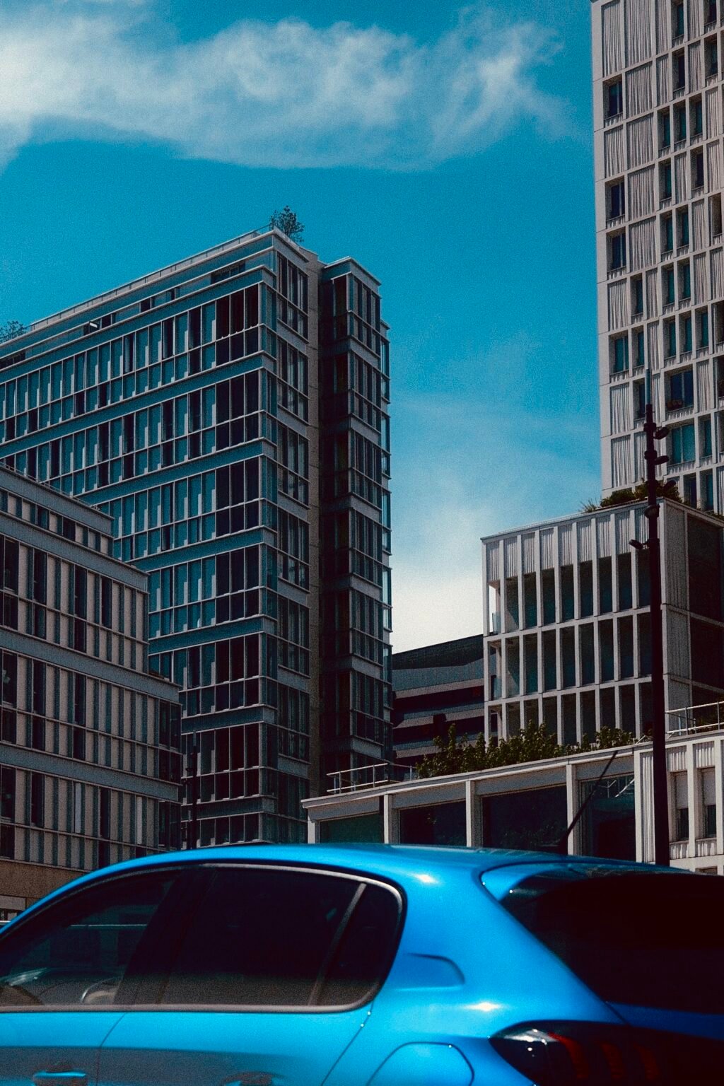 Immeubles modernes et voiture bleue sous un ciel bleu.