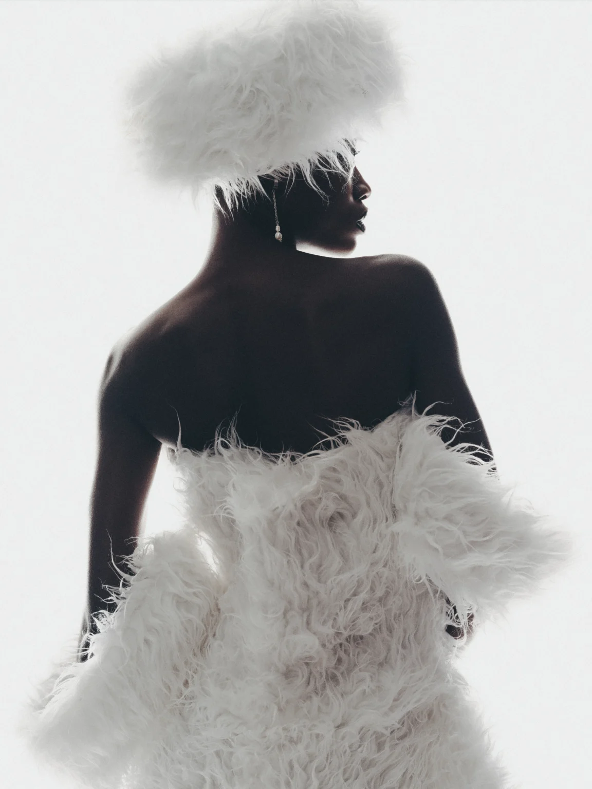 Portrait en noir et blanc d’une femme portant une tenue blanche à plumes.
