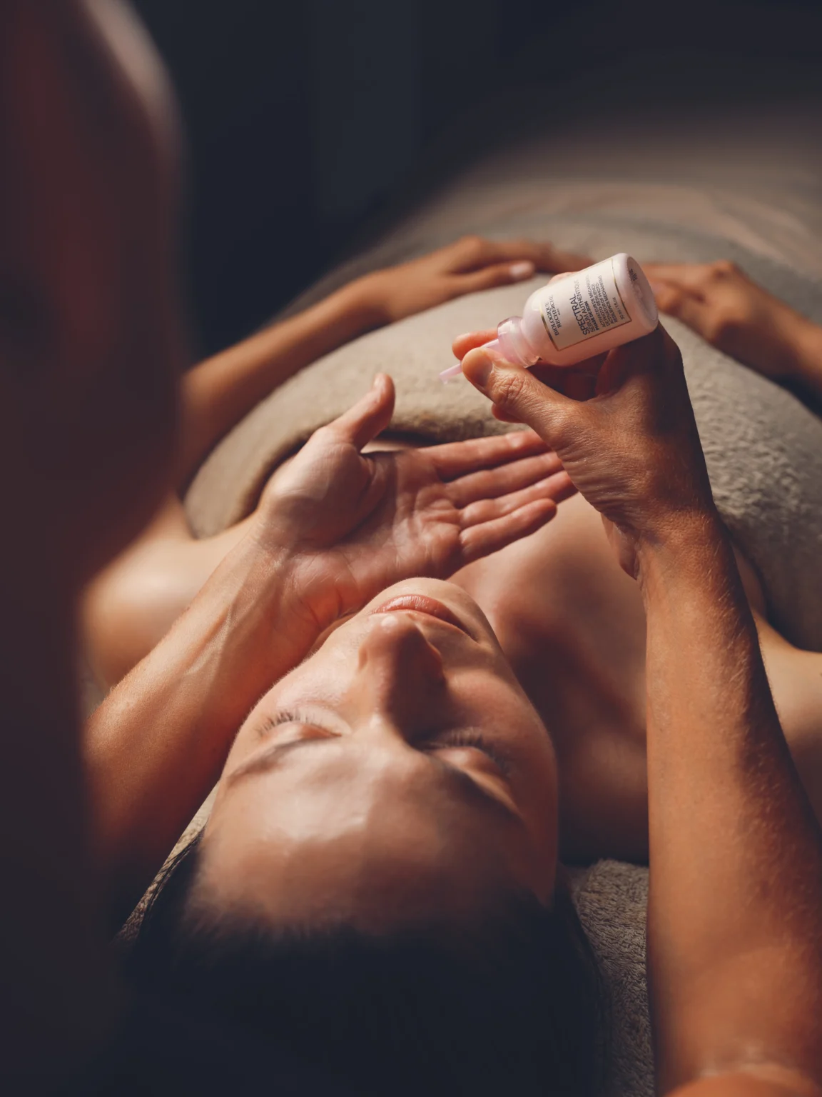 Cliente recevant un soin du visage avec un produit présenté au-dessus d’elle.