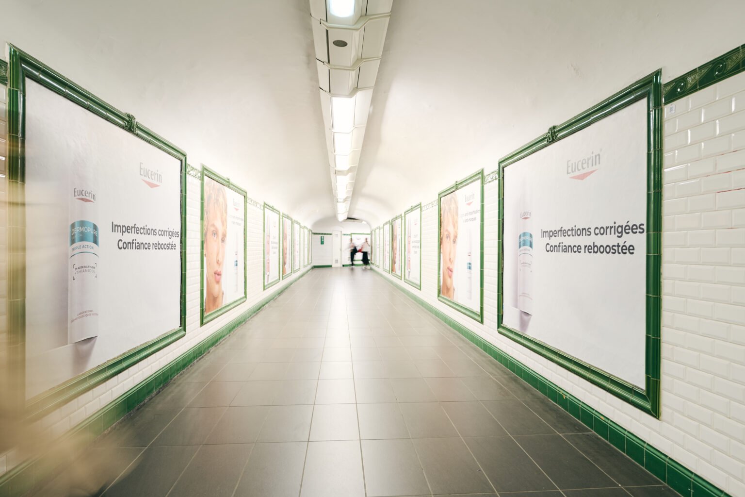 Couloir de métro bordé d’affiches publicitaires Eucerin.