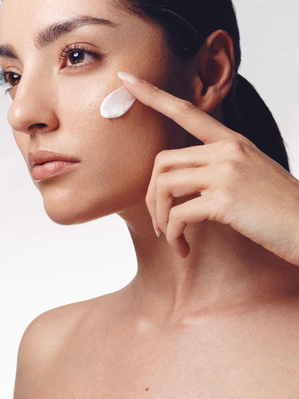 Femme appliquant une touche de crème sur sa joue.